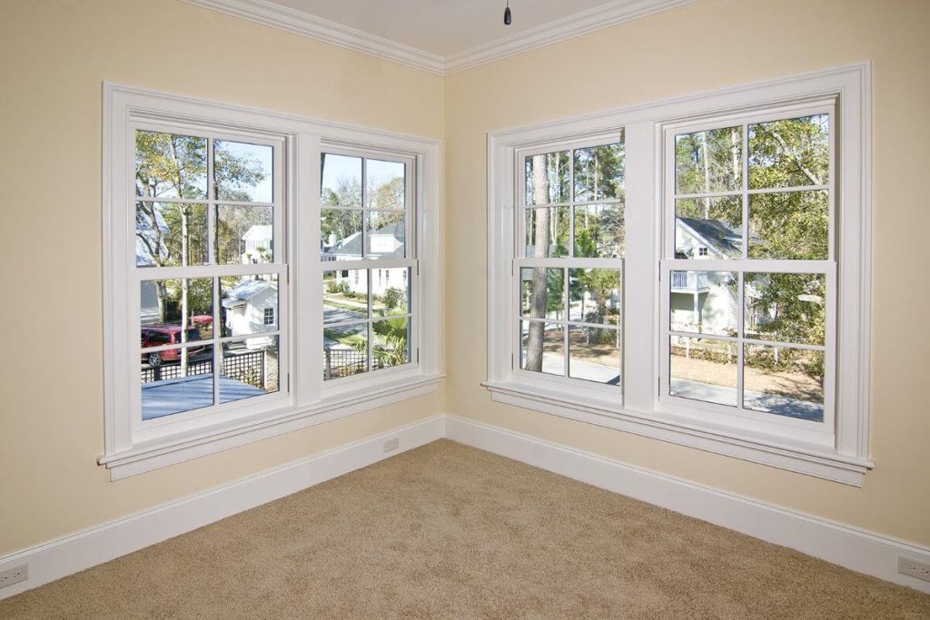 Interior room with white-framed aluminium sliding sash windows providing a clear view outside.